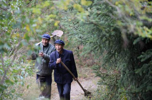 弟弟許志強（左）和哥哥許志剛扛著鐵鍁走過種著側柏和雲杉的小道。 