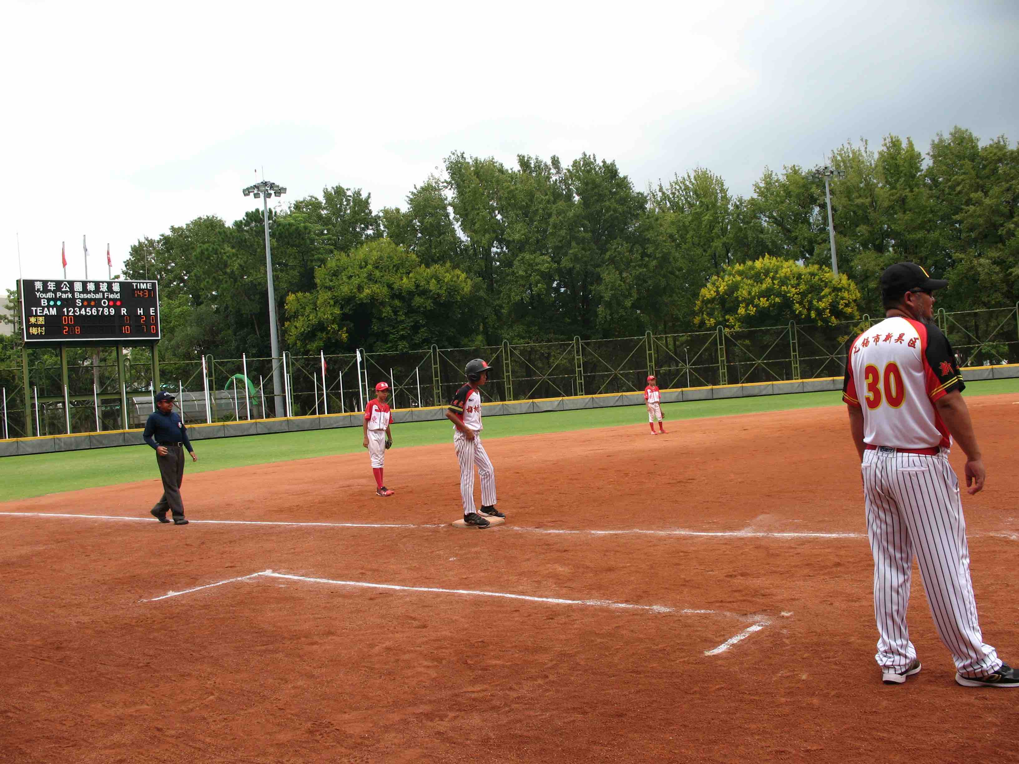 李偉教練站上三壘指導區給場上的無錫梅村實驗小學棒球隊小球員指導。